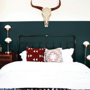Chambre à coucher avec lit en métal et crâne accroché au mur, mis en valeur par notre vert émeraude profond AMAZON - N°2030 Peintures 1825