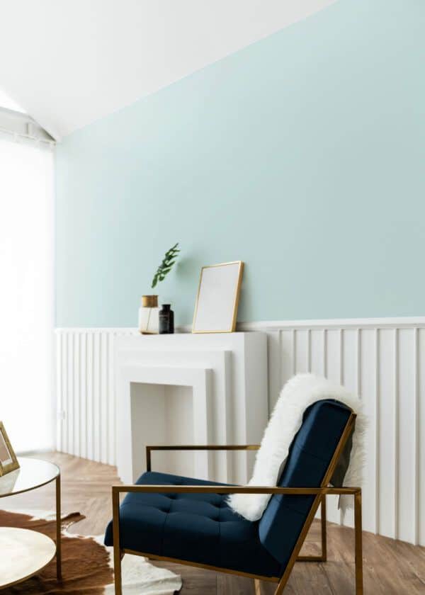 Salon avec fauteuil en velours bleu et cheminée blanche, mis en valeur par notre bleu glacial ARTIC N°1948 Peintures 1825