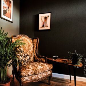 Salon avec fauteuil ancien et table en bois, mis en valeur par notre noir BLACK IS BACK - N°2015 Peintures 1825