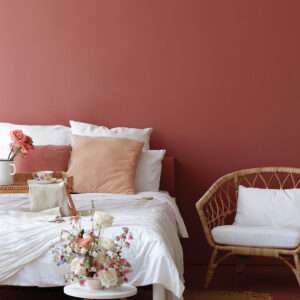 Chambre à coucher avec fauteuil en rotin et parure de lit blanche, mise en valeur par notre rouge brun terracotta CAYENNE - N°1873 Peintures 1825