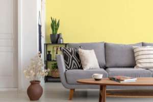 Salon avec canapé en tissu gris et table basse en bois, mis en valeur par notre jaune POP CORN - N°2019 Peintures 1825