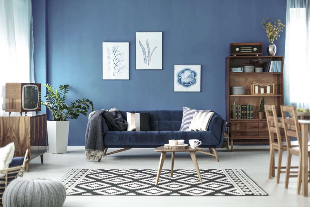 Salon avec canapé en velours bleu et meubles rétro en bois, mis en valeur par notre bleu JÄRVI - N°2077 Peintures 1825